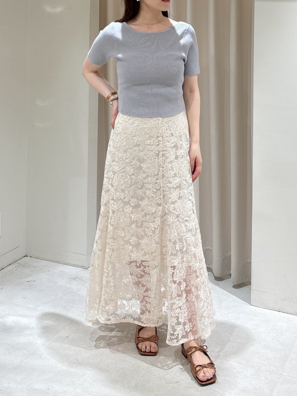 グレー系のニット/セーター、ホワイト系のスカート、ホワイト系のボストンバッグを着用したレディースの夏コーディネートの2枚目の写真