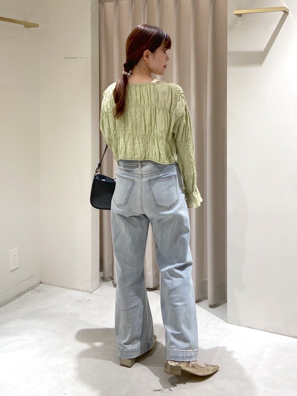 グリーン系のカーディガン/ボレロ、ブルー系のデニムパンツ、ホワイト系のタンクトップを着用したレディースの春コーディネートの2枚目の写真