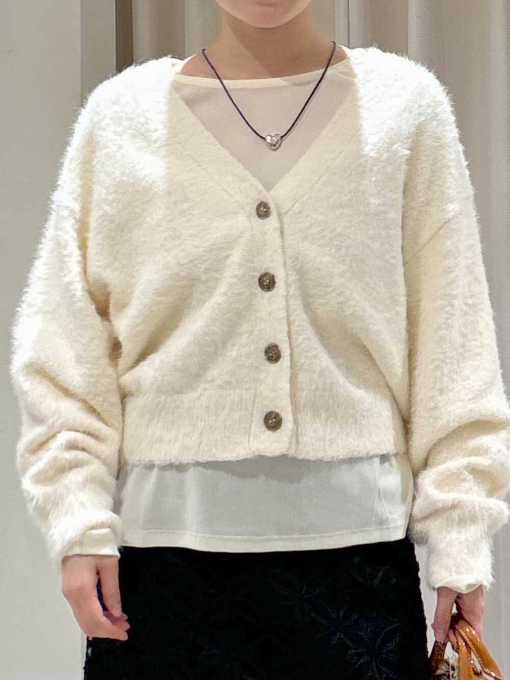 ブラック系のスカート、ベージュ系のショルダーバッグ、ブラック系のブーツを着用したレディースの冬コーディネートの2枚目の写真