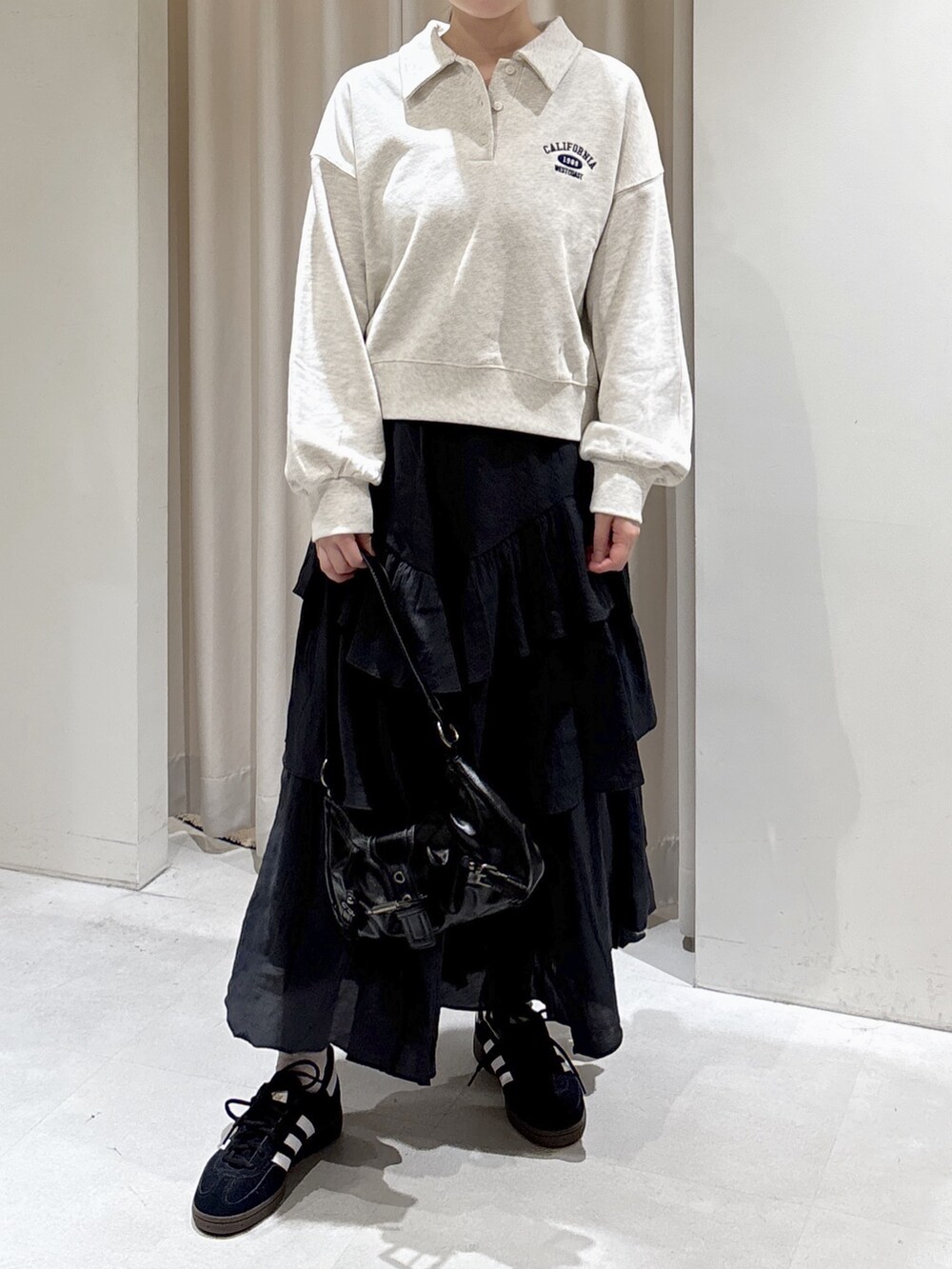 ホワイト系のスウェット、ブラック系のスカート、ブラック系のショルダーバッグを着用したレディースの秋コーディネートの2枚目の写真
