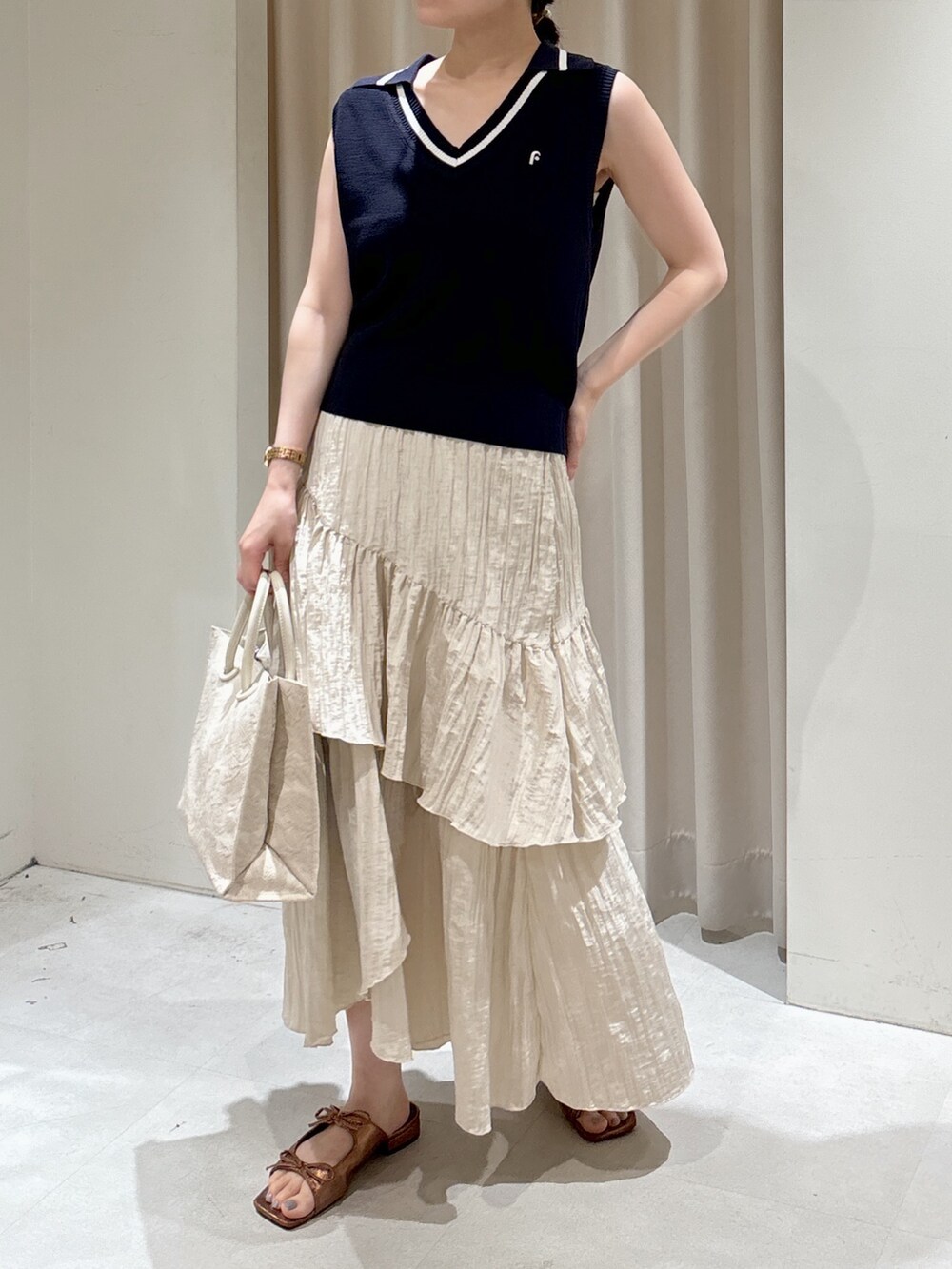 ホワイト系のトートバッグ、ホワイト系のスカート、ブラウン系のサンダルを着用したレディースの夏コーディネートの3枚目の写真