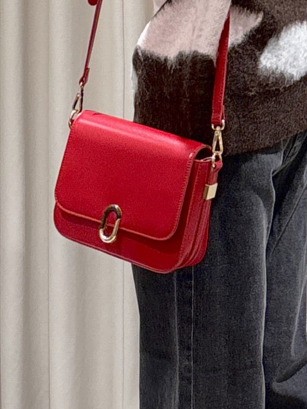 ブラウン系のニット/セーター、レッド系のハンドバッグ、ブラック系のデニムパンツを着用したレディースの秋コーディネートの4枚目の写真