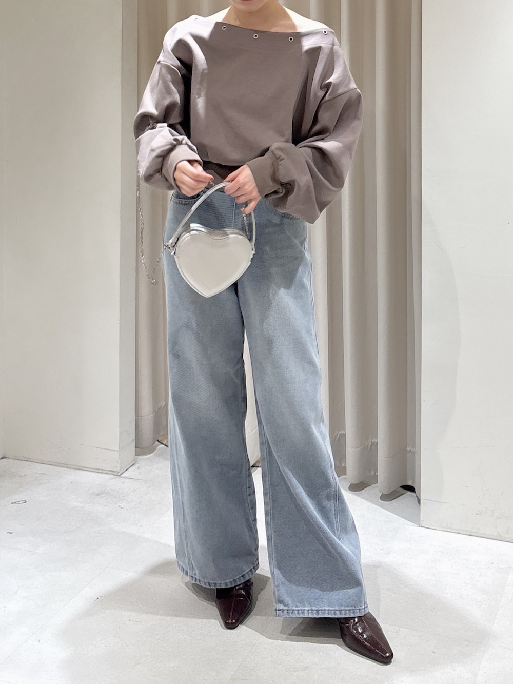 ブラウン系のスウェット、ブルー系のデニムパンツ、シルバー系のショルダーバッグを着用したレディースの冬コーディネートの4枚目の写真