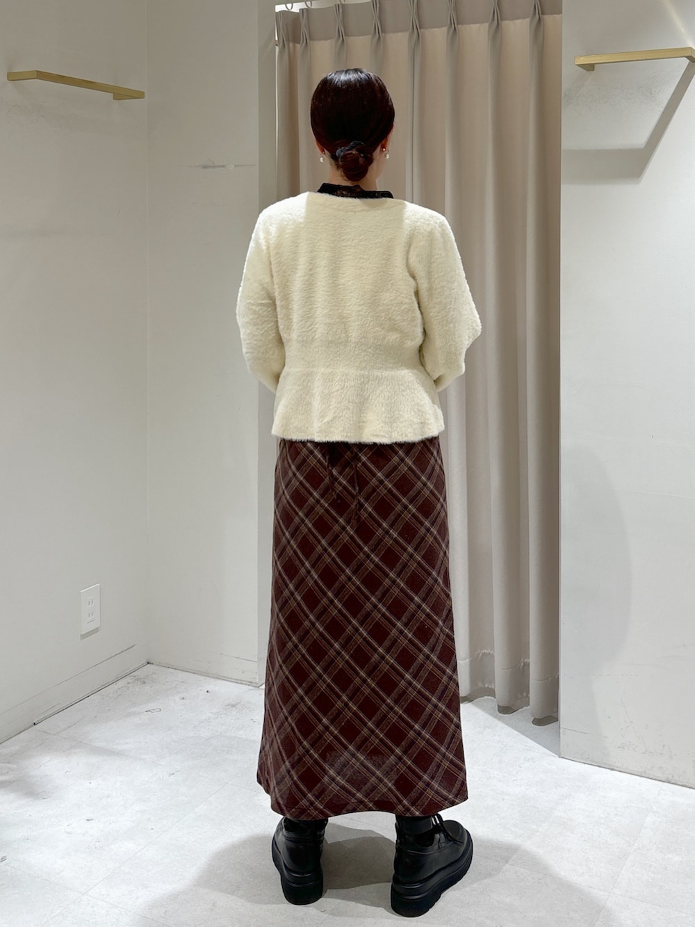 ブラウン系のワンピース、ホワイト系のカーディガン/ボレロ、ブラック系のTシャツ/カットソーを着用したレディースの冬コーディネートの3枚目の写真