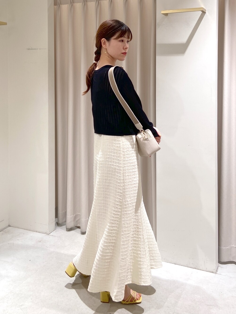 ホワイト系のワンピース、ブラック系のカーディガン/ボレロ、ホワイト系のボディバッグ/ウエストポーチを着用したレディースの春コーディネートの2枚目の写真