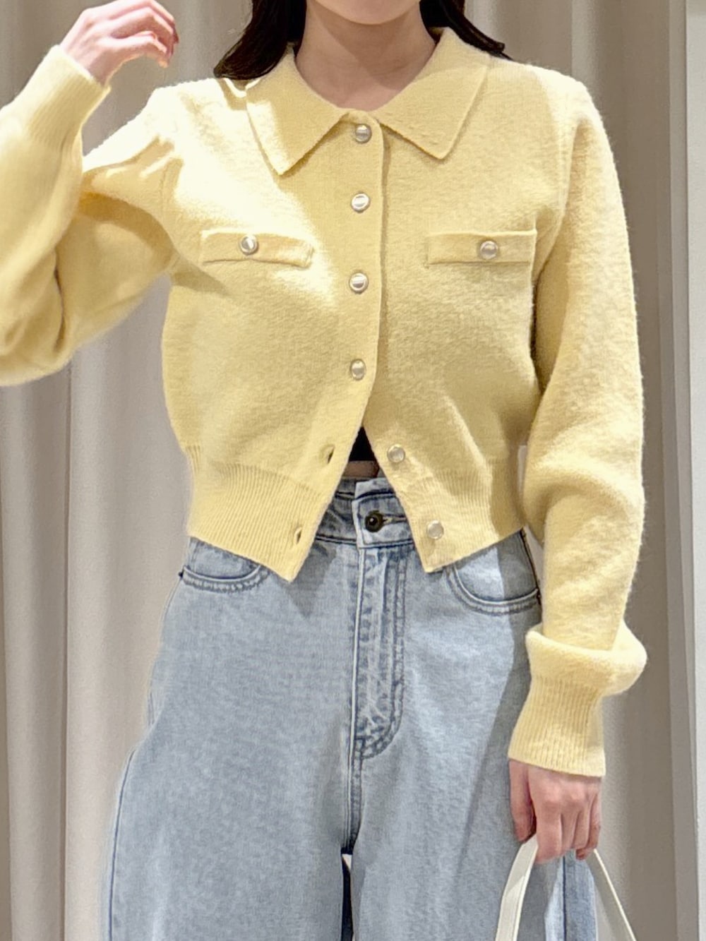 イエロー系のニット/セーター、ブラウン系のパンプス、ブルー系のデニムパンツを着用したレディースの冬コーディネートの3枚目の写真