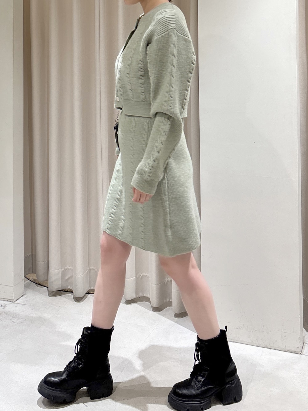 グリーン系のワンピース、ブラック系のブーツ、ブラック系のショルダーバッグを着用したレディースの冬コーディネートの2枚目の写真