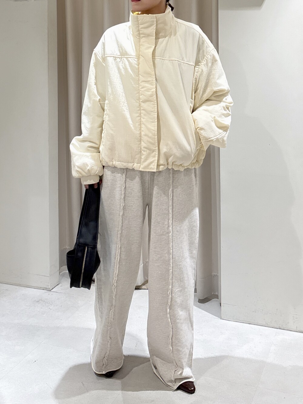 ホワイト系のブルゾン、ブラック系のハンドバッグ、ホワイト系のスウェットパンツを着用したレディースの秋コーディネートの2枚目の写真