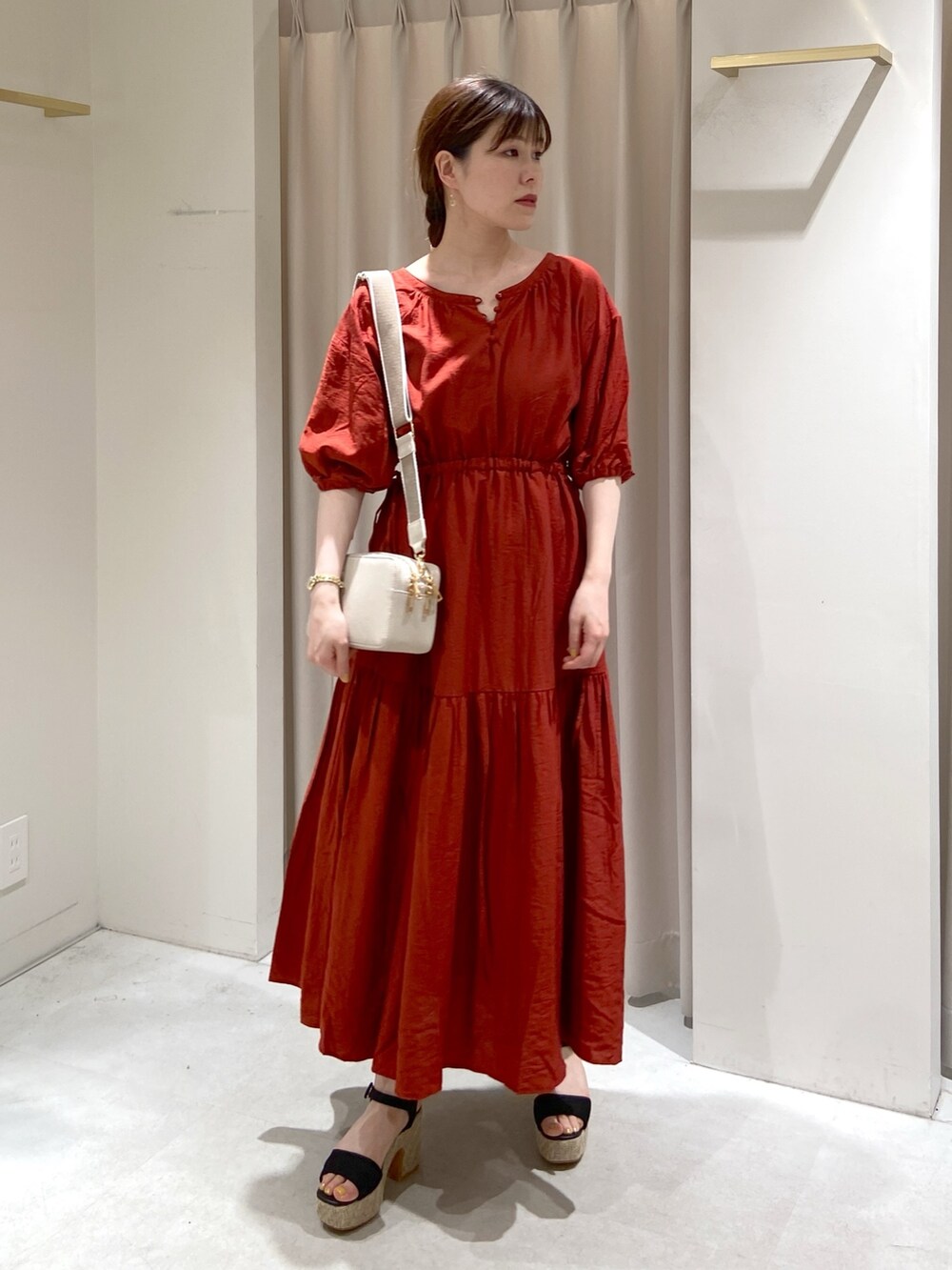 レッド系のワンピース、ホワイト系のボディバッグ/ウエストポーチ、ブラック系のサンダルを着用したレディースの春コーディネートの3枚目の写真
