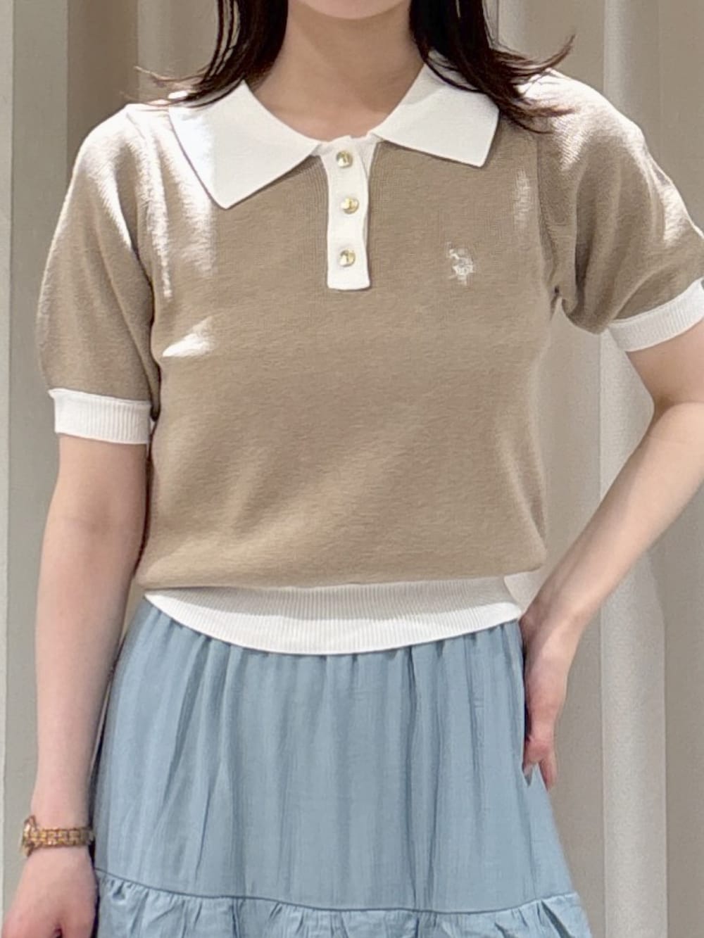 ベージュ系のニット/セーター、ブルー系のスカート、ホワイト系のトートバッグを着用したレディースの春コーディネートの2枚目の写真