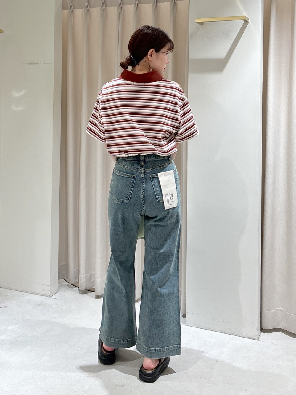 レッド系のポロシャツ、ブラック系のキャミソール、グリーン系のトートバッグを着用したレディースの春コーディネートの3枚目の写真