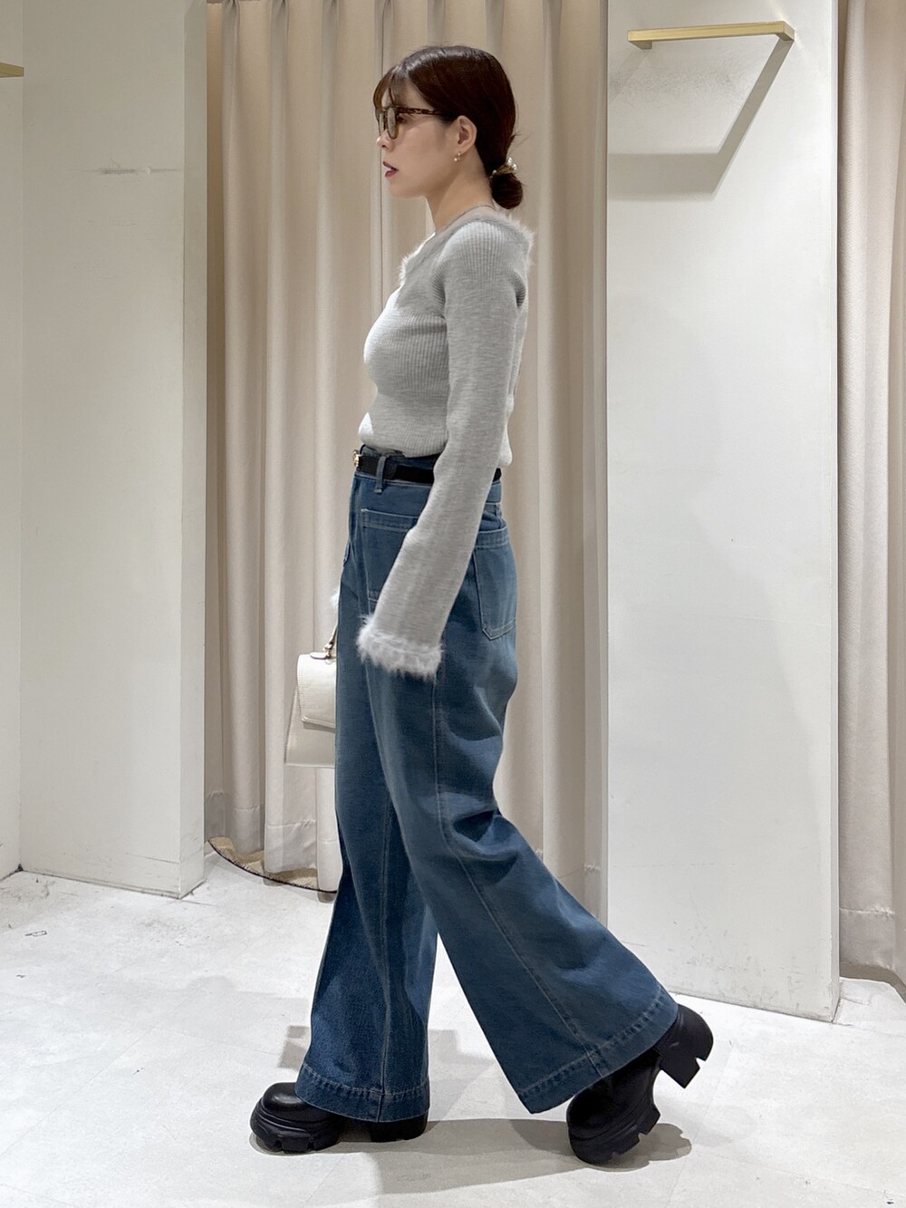 グレー系のニット/セーター、ブルー系のデニムパンツ、ホワイト系のトートバッグを着用したレディースの秋コーディネートの4枚目の写真