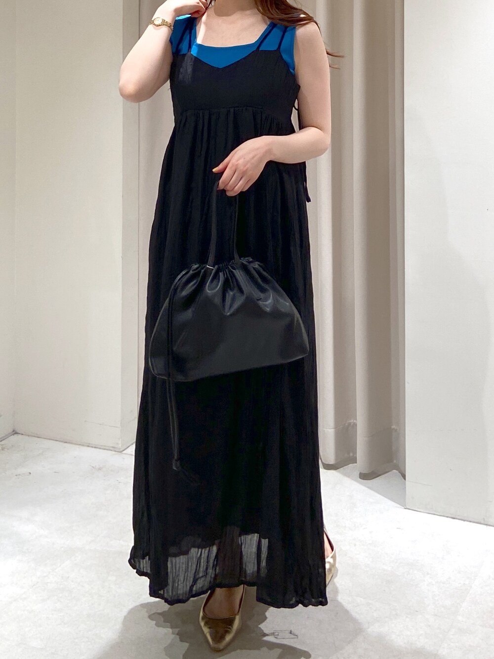 ブルー系のタンクトップ、ブラック系のハンドバッグ、ゴールド系のパンプスを着用したレディースの春コーディネートの3枚目の写真