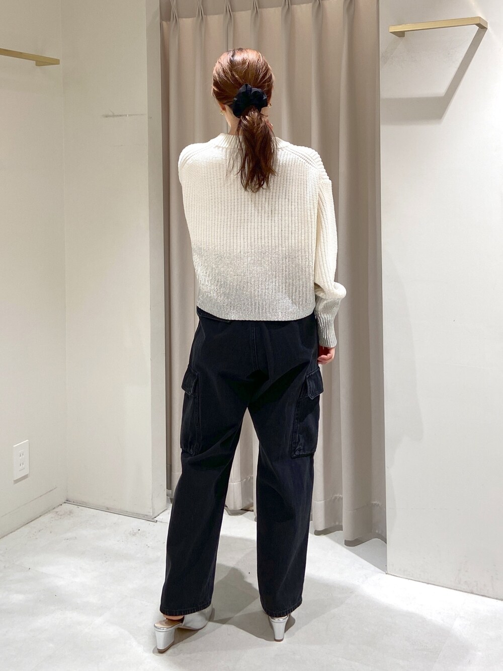 ホワイト系のニット/セーター、グリーン系のトートバッグ、ブラック系のデニムパンツを着用したレディースの冬コーディネートの3枚目の写真