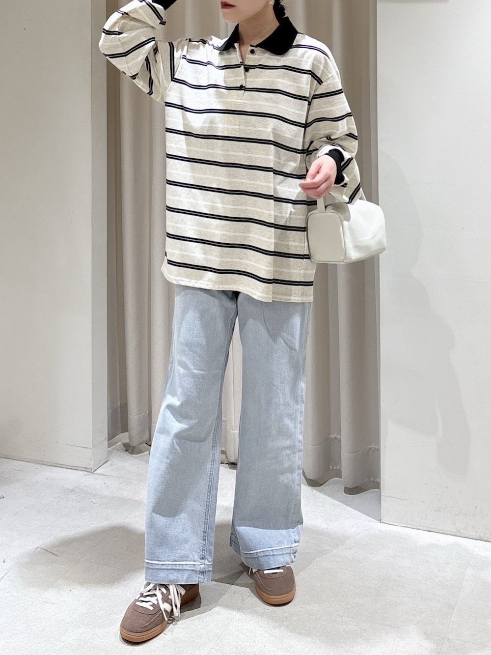 グレー系のTシャツ/カットソー、ホワイト系のハンドバッグ、ブルー系のデニムパンツを着用したレディースの春コーディネートの4枚目の写真