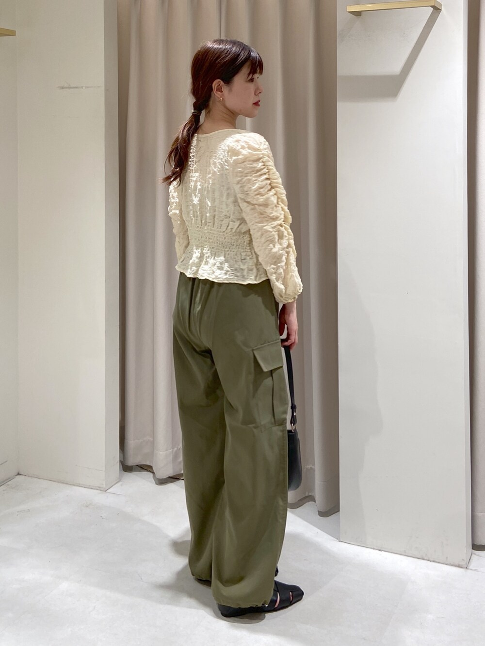 ホワイト系のカーディガン/ボレロ、グレー系のキャミソール、ブラック系のショルダーバッグを着用したレディースの春コーディネートの2枚目の写真