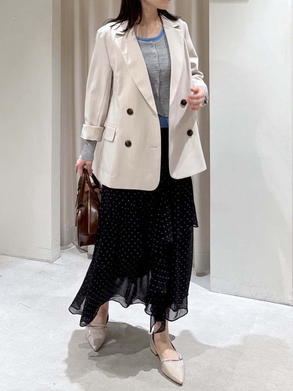 ベージュ系のブルゾン、グレー系のニット/セーター、ブラウン系のハンドバッグを着用したレディースの春コーディネートの2枚目の写真