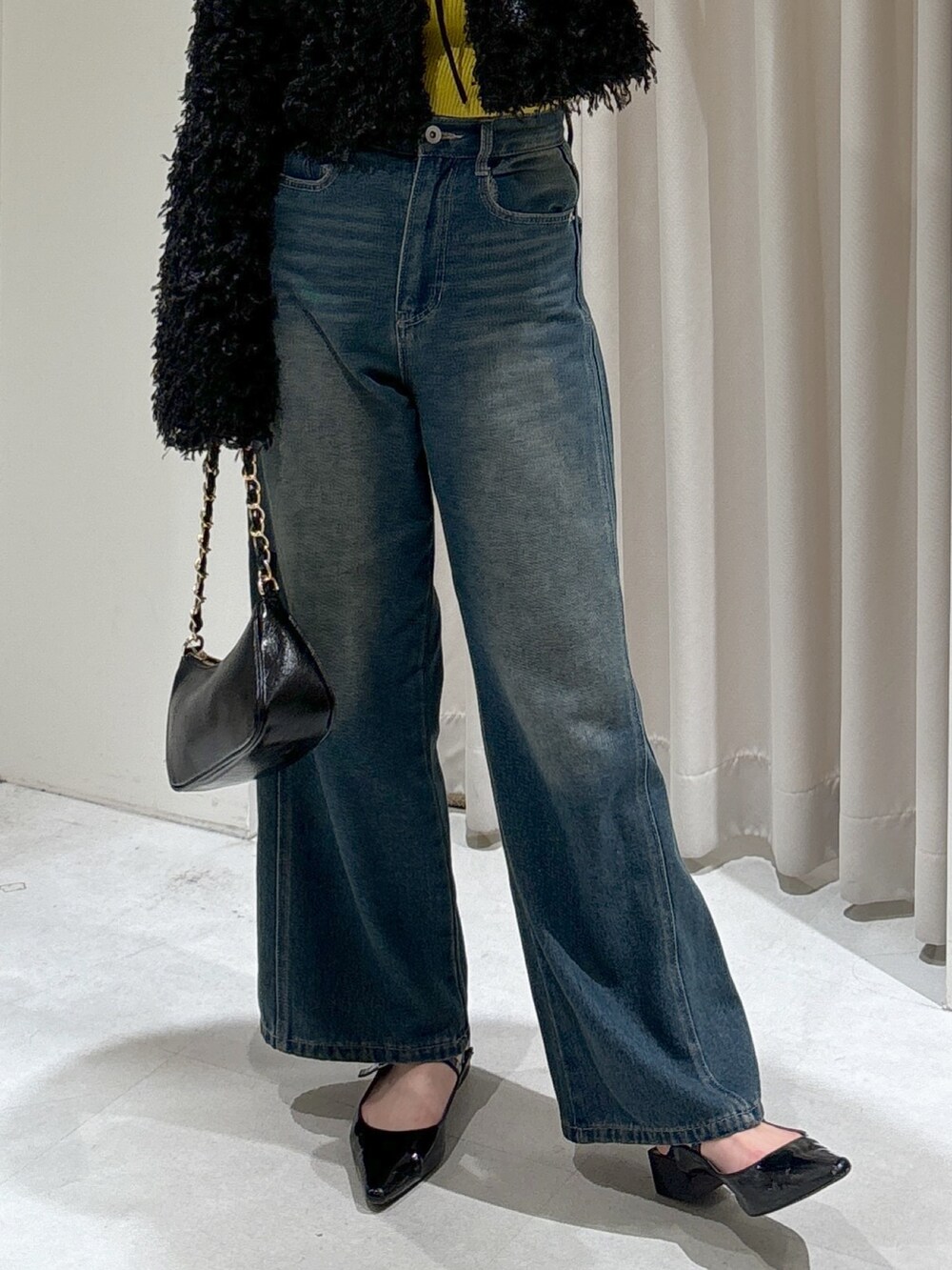 ブラック系のカーディガン/ボレロ、イエロー系のニット/セーター、ブルー系のデニムパンツを着用したレディースの秋コーディネートの7枚目の写真