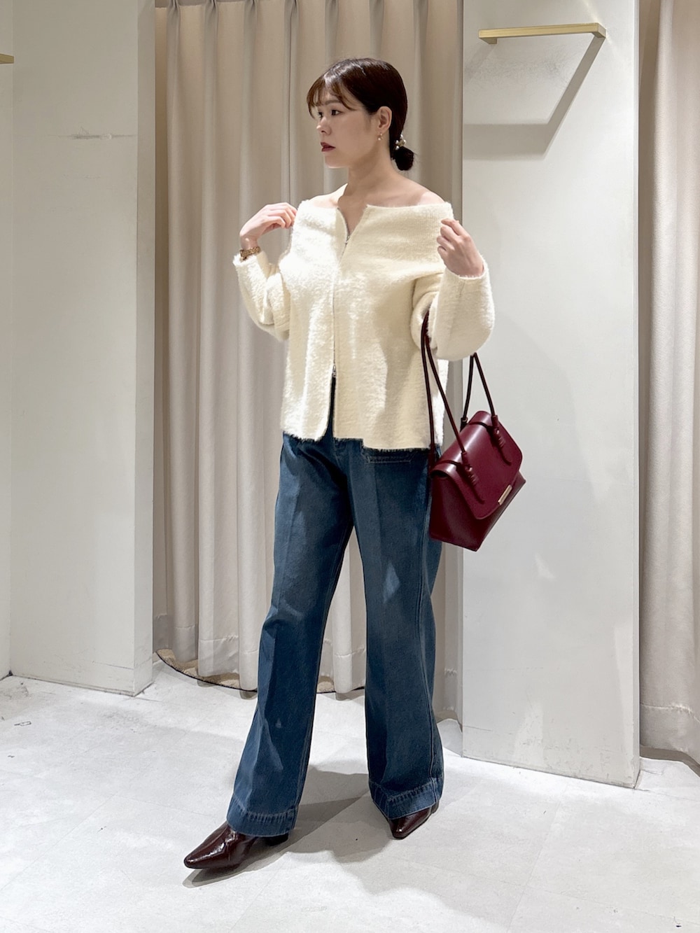 ホワイト系のニット/セーター、レッド系のトートバッグ、ブルー系のデニムパンツを着用したレディースの秋コーディネートの4枚目の写真