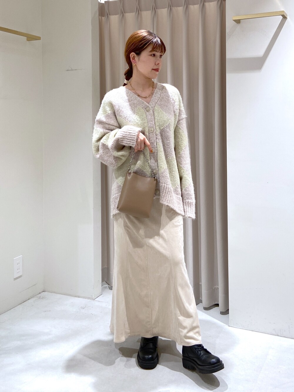 ベージュ系のショルダーバッグ、ブラック系のブーツ、ホワイト系のスカートを着用したレディースの秋コーディネートの2枚目の写真