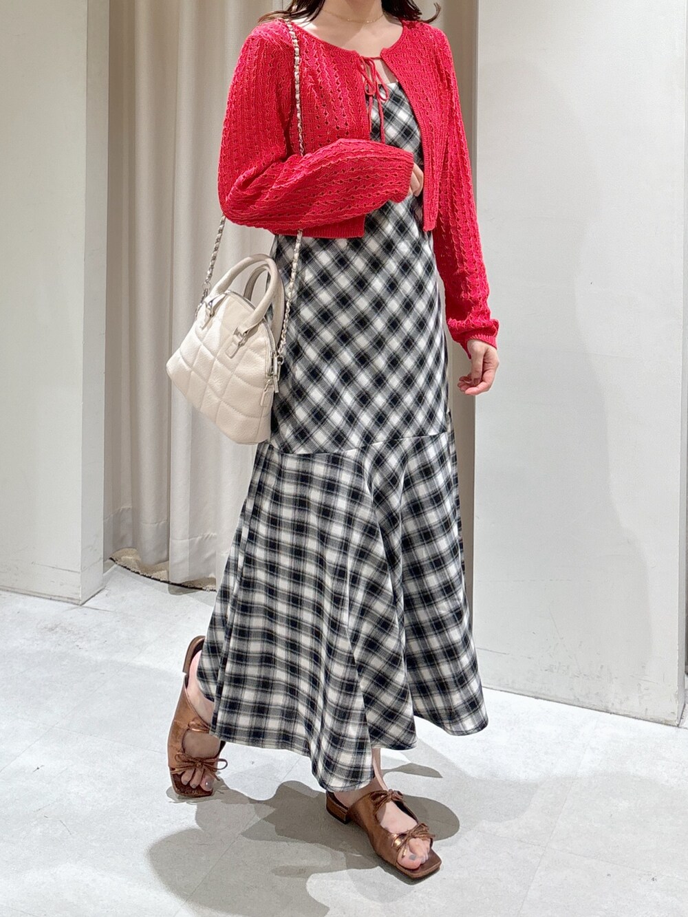 レッド系のカーディガン/ボレロ、ブラック系のワンピース、ホワイト系のトートバッグを着用したレディースの夏コーディネートの2枚目の写真