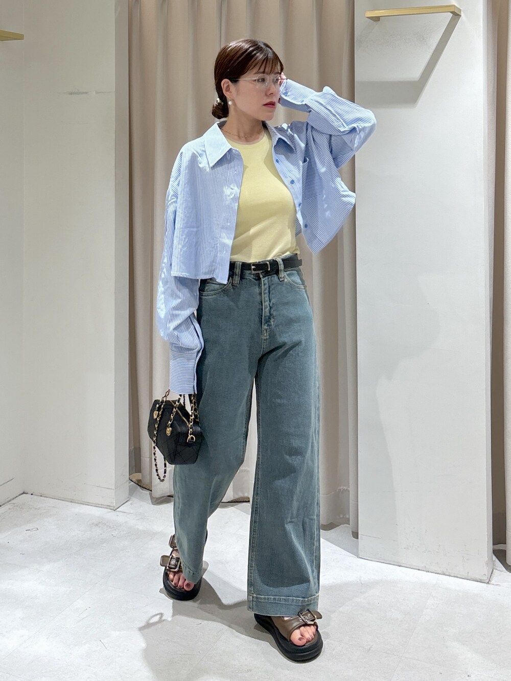 ブルー系のシャツ/ブラウス、イエロー系のタンクトップ、ブラック系のショルダーバッグを着用したレディースの夏コーディネートの2枚目の写真