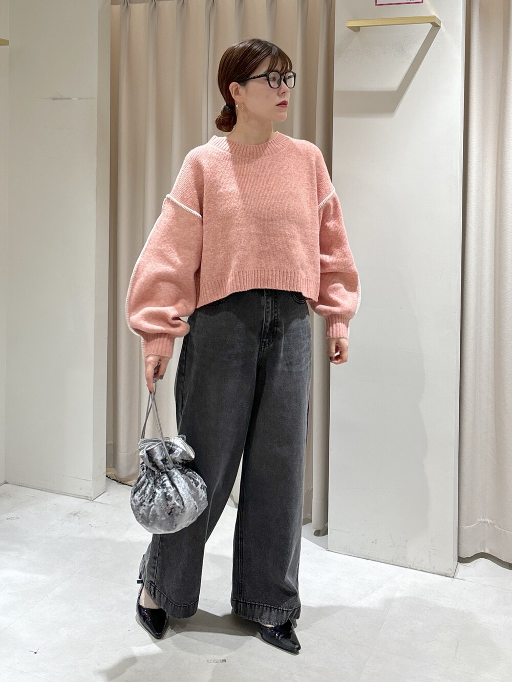 ピンク系のニット/セーター、ブラック系のデニムパンツ、グレー系のハンドバッグを着用したレディースの秋コーディネートの2枚目の写真