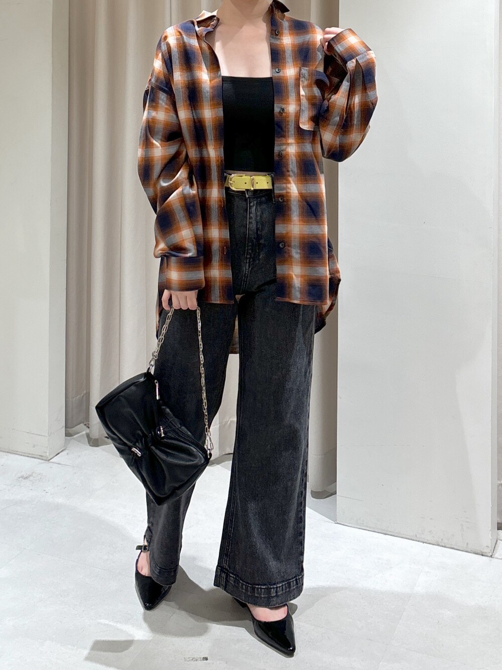 オレンジ系のシャツ/ブラウス、ブラック系のキャミソール、ブラック系のデニムパンツを着用したレディースの秋コーディネートの3枚目の写真