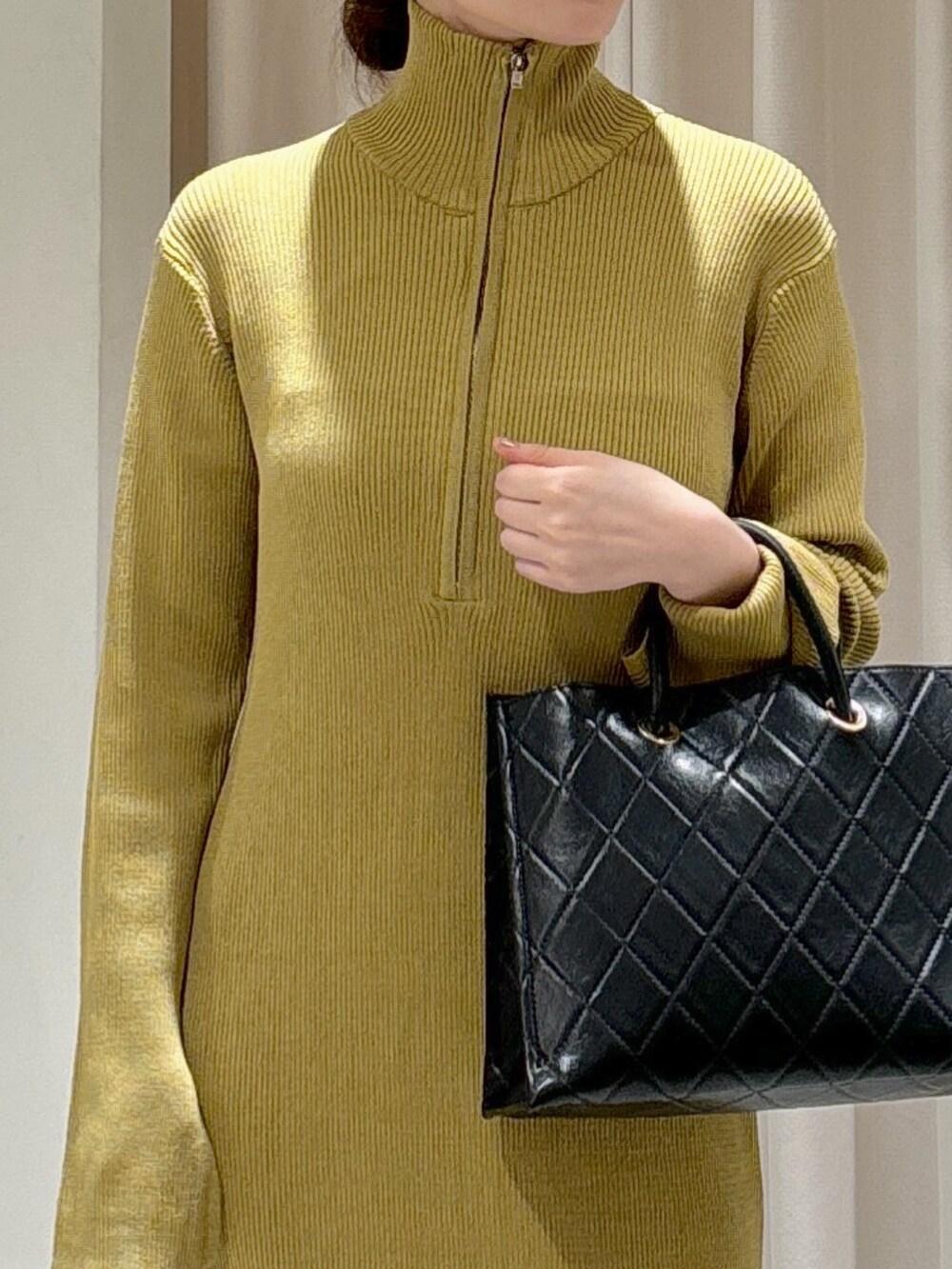 ブラック系のショルダーバッグ、ブラック系のパンプス、グリーン系のワンピースを着用したレディースの秋コーディネートの3枚目の写真