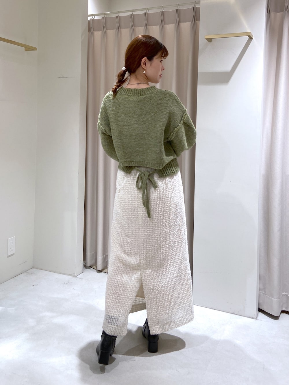 グリーン系のニット/セーター、ホワイト系のスカート、ベージュ系のショルダーバッグを着用したレディースの秋コーディネートの4枚目の写真