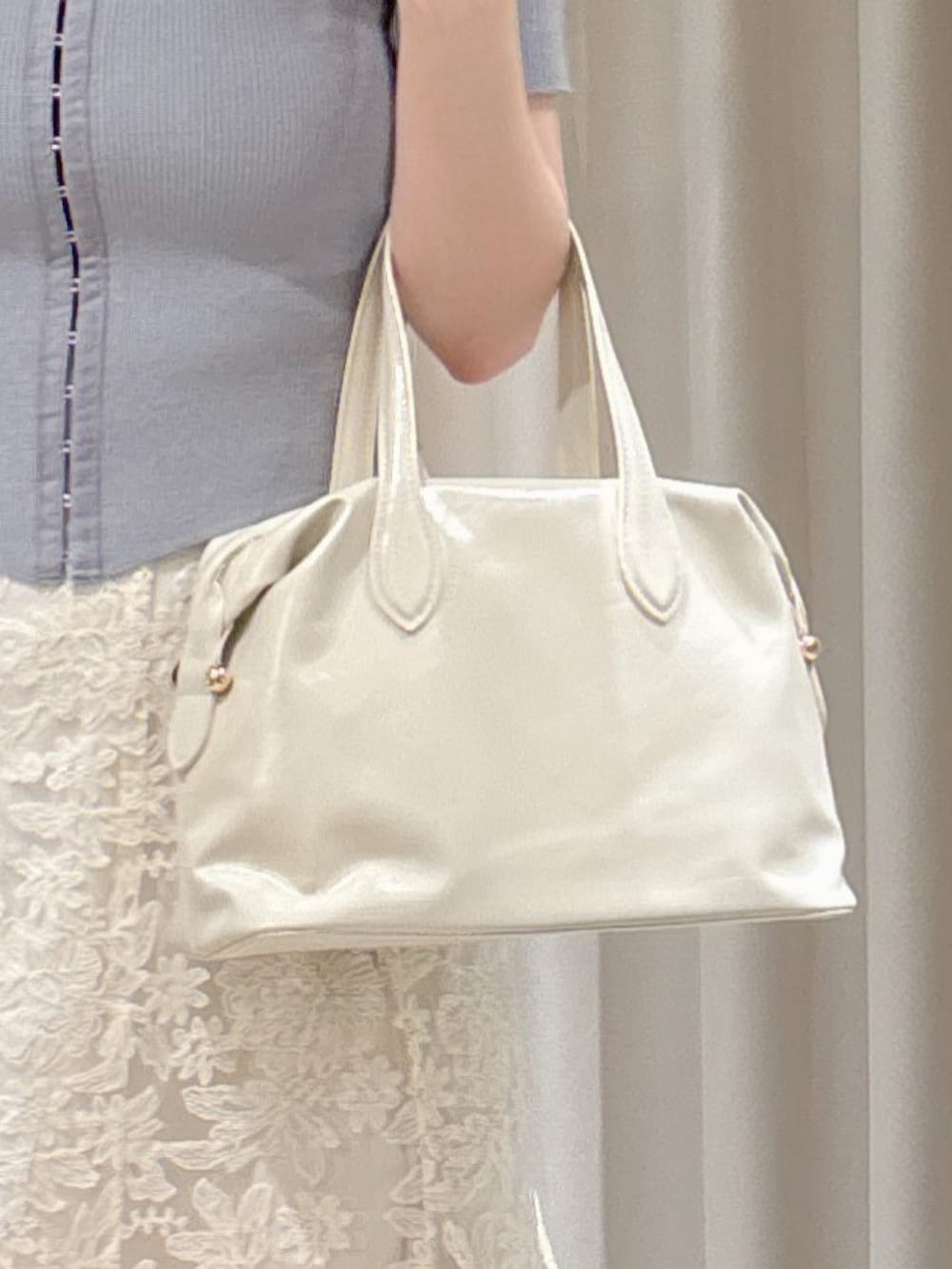 グレー系のニット/セーター、ホワイト系のスカート、ホワイト系のボストンバッグを着用したレディースの夏コーディネートの5枚目の写真