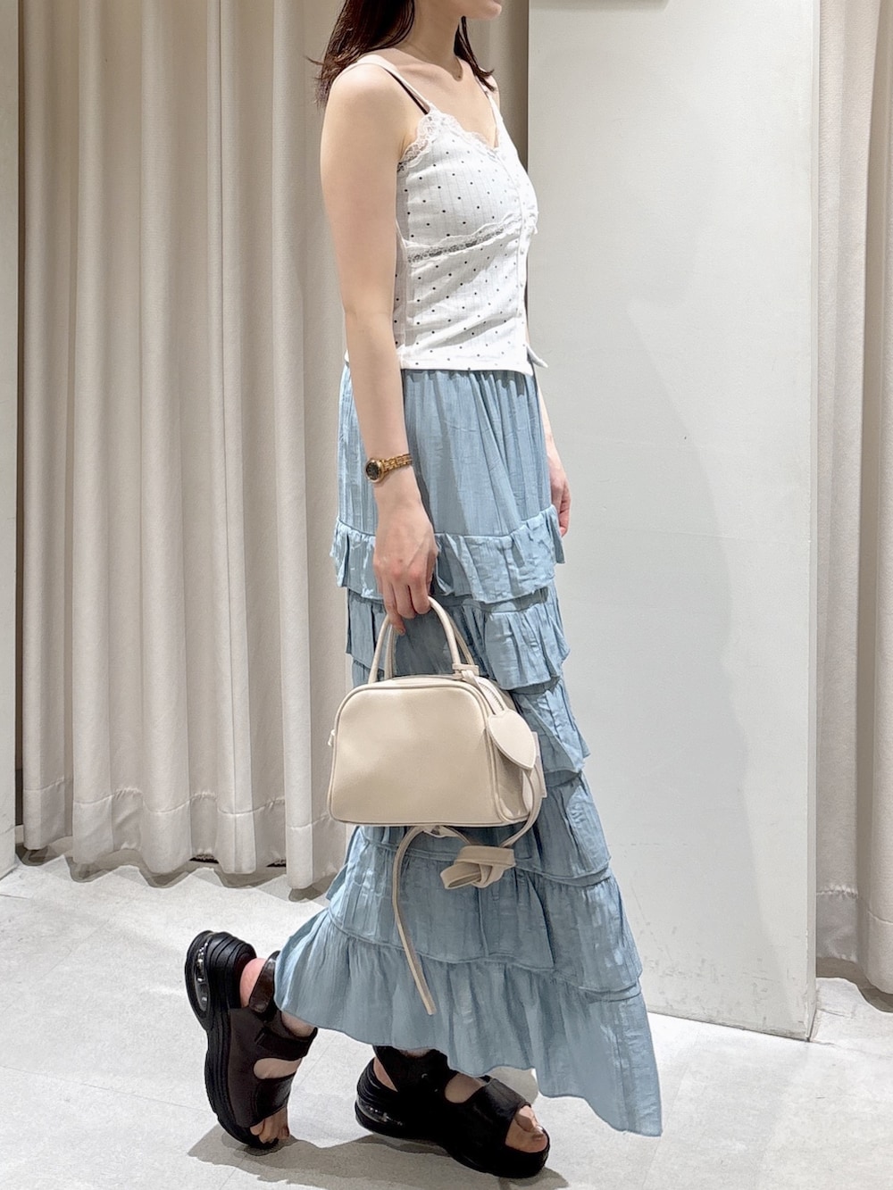 ブルー系のスカート、ブラウン系のサンダル、ホワイト系のボストンバッグを着用したレディースの夏コーディネートの3枚目の写真