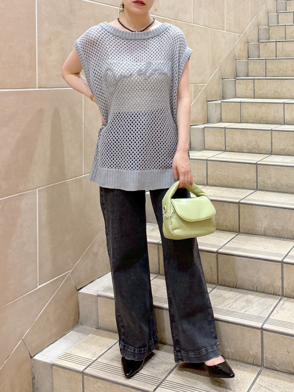 グレー系のニット/セーター、ホワイト系のキャミソール、グリーン系のショルダーバッグを着用したレディースの夏コーディネートの2枚目の写真