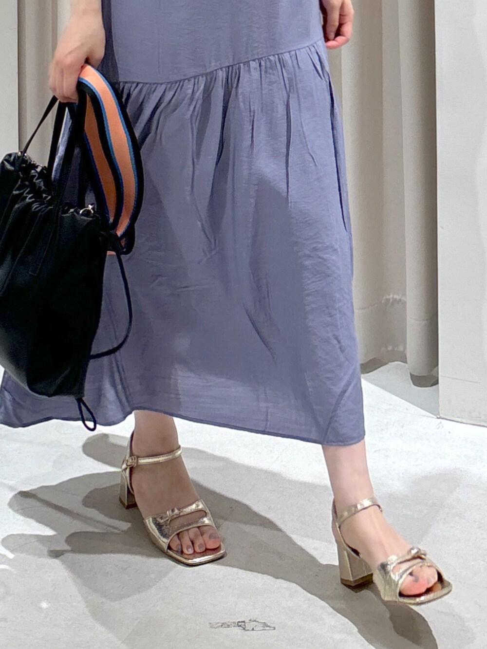 ブルー系のワンピース、ブラック系のハンドバッグ、ゴールド系のサンダルを着用したレディースの夏コーディネートの2枚目の写真