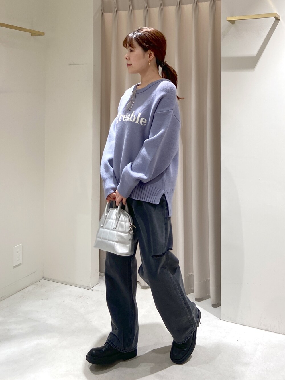 ベージュ系のノーカラーコート、ブルー系のニット/セーター、ブラック系のショルダーバッグを着用したレディースの冬コーディネートの5枚目の写真