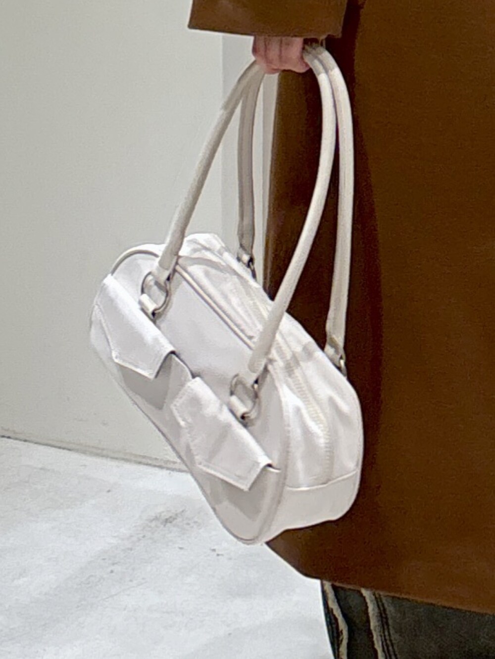 ブラウン系のチェスターコート、ブラック系のニット/セーター、ホワイト系のトートバッグを着用したレディースの秋コーディネートの5枚目の写真