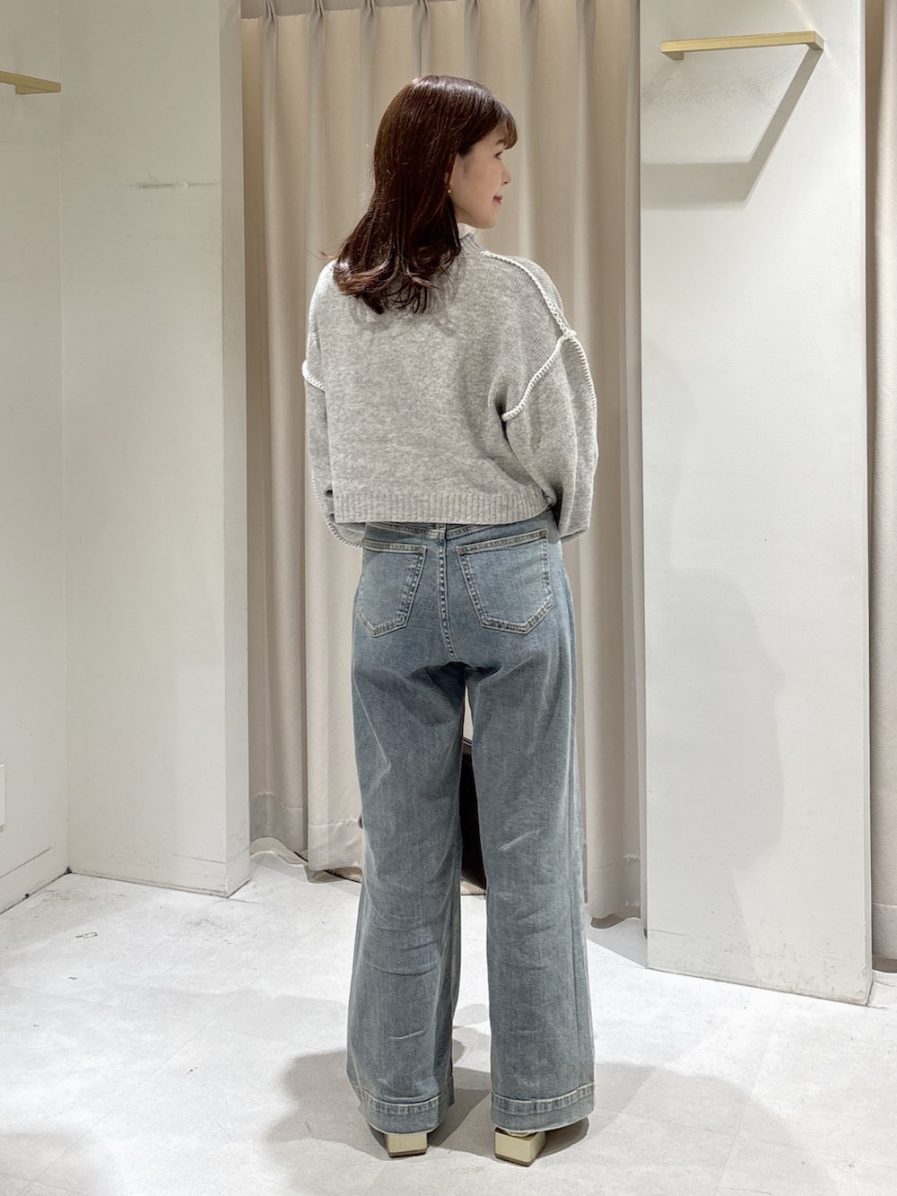 ブラウン系のステンカラーコート、ブルー系のトートバッグ、ブルー系のデニムパンツを着用したレディースの秋コーディネートの7枚目の写真