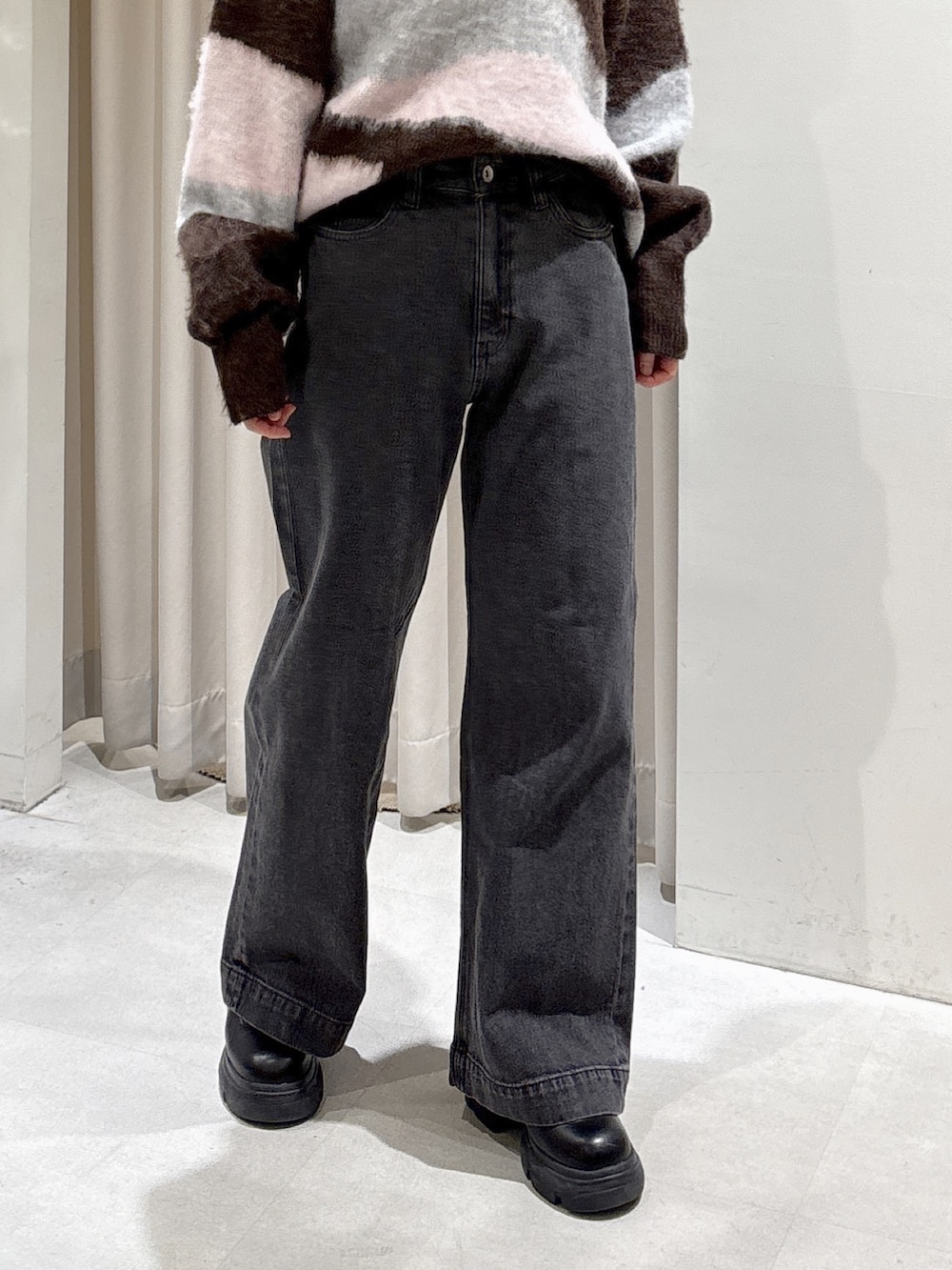 ブラウン系のニット/セーター、レッド系のハンドバッグ、ブラック系のデニムパンツを着用したレディースの秋コーディネートの5枚目の写真