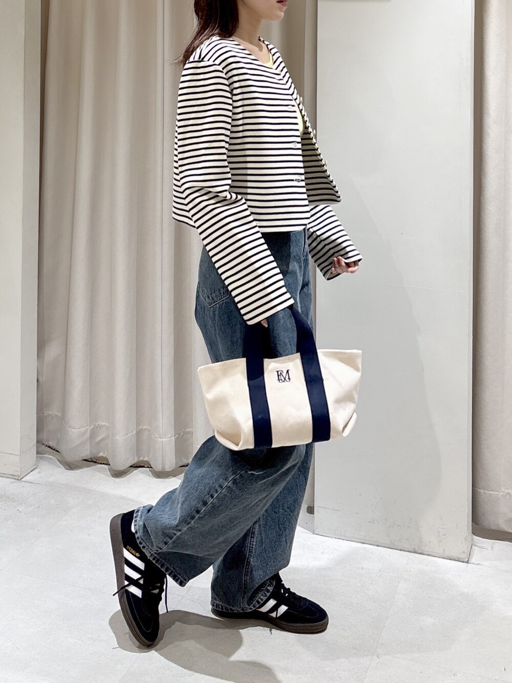 ブラック系のノーカラージャケット、イエロー系のニット/セーター、ブルー系のデニムパンツを着用したレディースの冬コーディネートの4枚目の写真