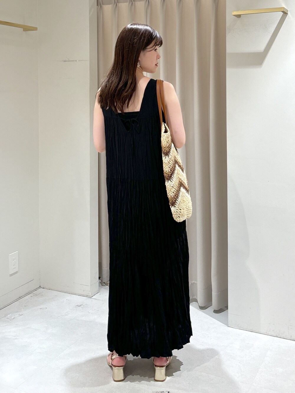 ブラック系のワンピース、ベージュ系のトートバッグ、ゴールド系のサンダルを着用したレディースの夏コーディネートの5枚目の写真