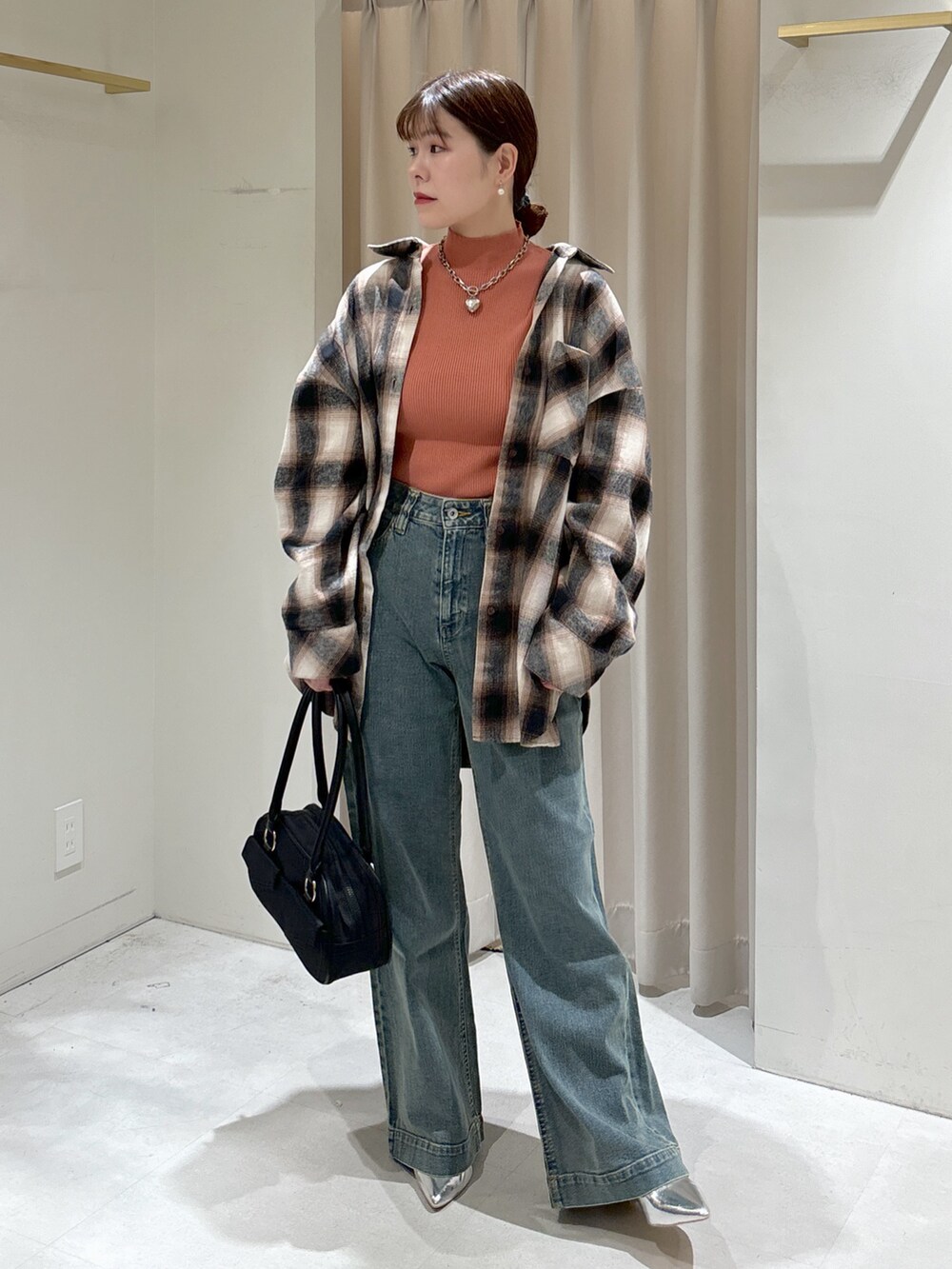 ブラウン系のシャツ/ブラウス、ピンク系のニット/セーター、ブラック系のトートバッグを着用したレディースの冬コーディネートの2枚目の写真