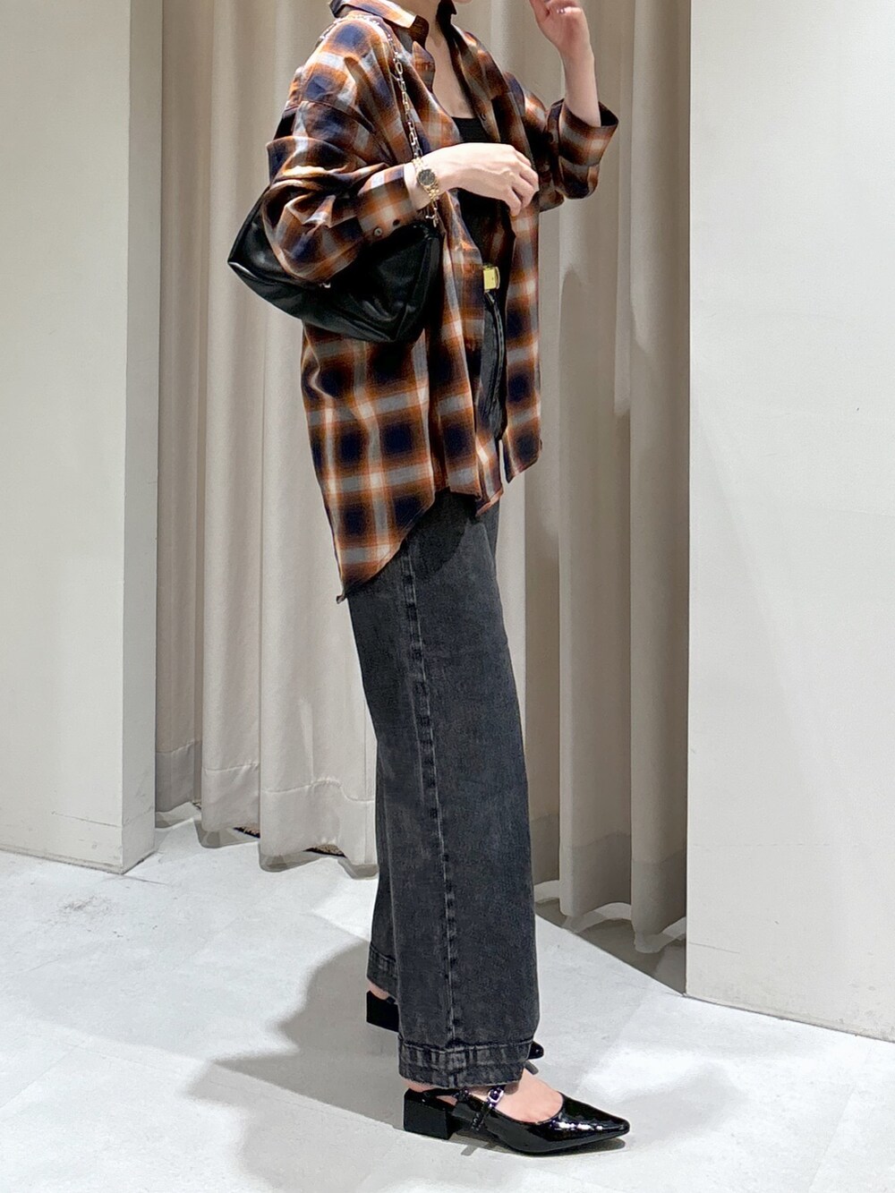 オレンジ系のシャツ/ブラウス、ブラック系のキャミソール、ブラック系のデニムパンツを着用したレディースの秋コーディネートの9枚目の写真