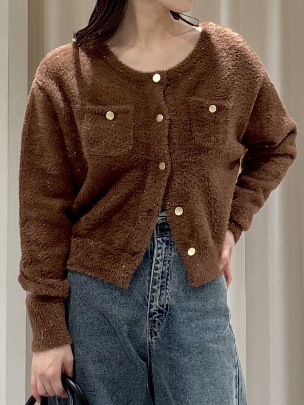 ブラウン系のニット/セーター、ブラック系のハンドバッグ、ブルー系のデニムパンツを着用したレディースの冬コーディネートの2枚目の写真