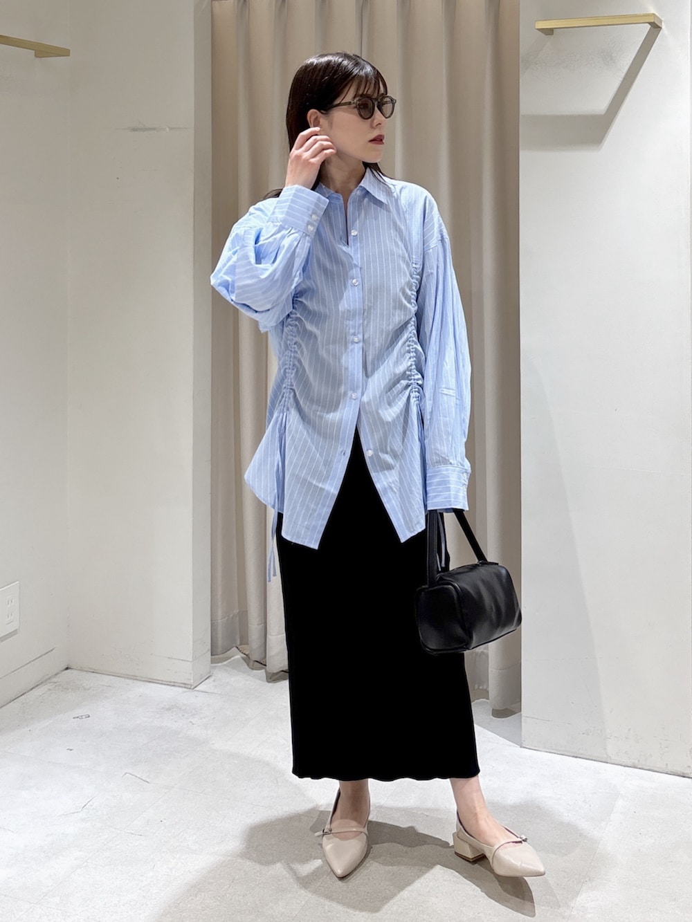 ブルー系のシャツ/ブラウス、ブラック系のハンドバッグ、ブラック系のスカートを着用したレディースの春コーディネートの2枚目の写真