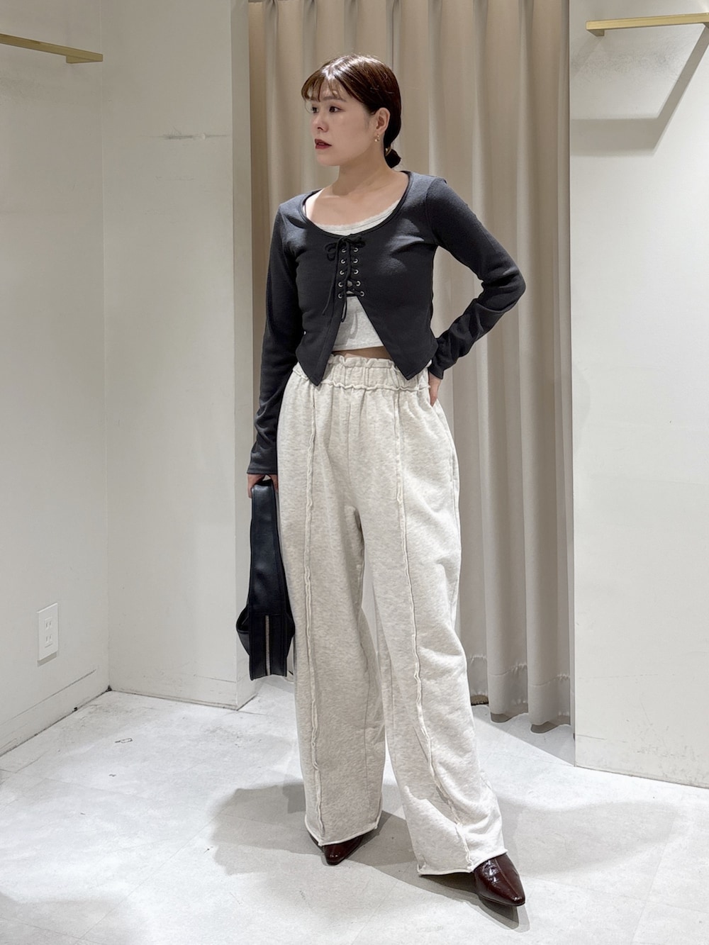 ホワイト系のブルゾン、ブラック系のハンドバッグ、ホワイト系のスウェットパンツを着用したレディースの秋コーディネートの6枚目の写真