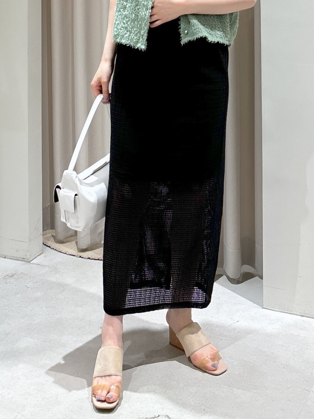 ブラック系のスカート、グレー系のサンダル、ホワイト系のハンドバッグを着用したレディースの夏コーディネートの6枚目の写真