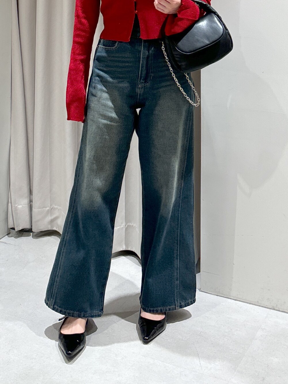 レッド系のニット/セーター、ブルー系のデニムパンツ、ブラック系のショルダーバッグを着用したレディースの秋コーディネートの5枚目の写真