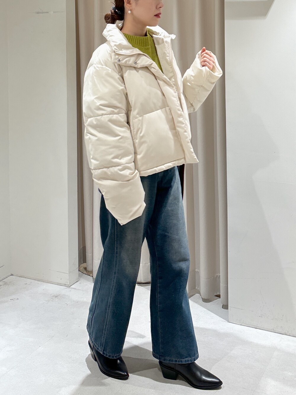 グリーン系のニット/セーター、ブルー系のデニムパンツ、ブラウン系のショルダーバッグを着用したレディースの冬コーディネートの7枚目の写真