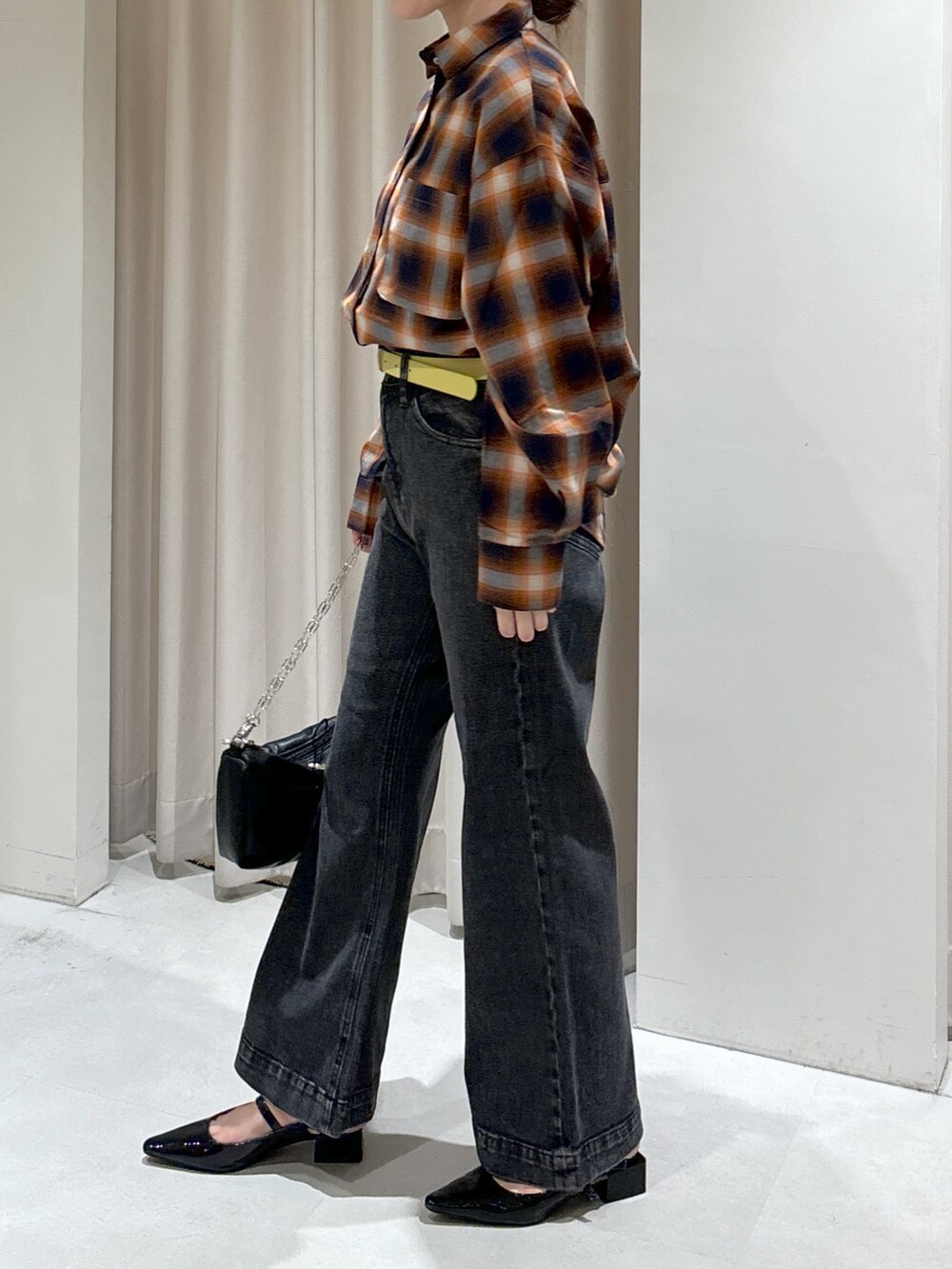 オレンジ系のシャツ/ブラウス、ブラック系のキャミソール、ブラック系のデニムパンツを着用したレディースの秋コーディネートの6枚目の写真