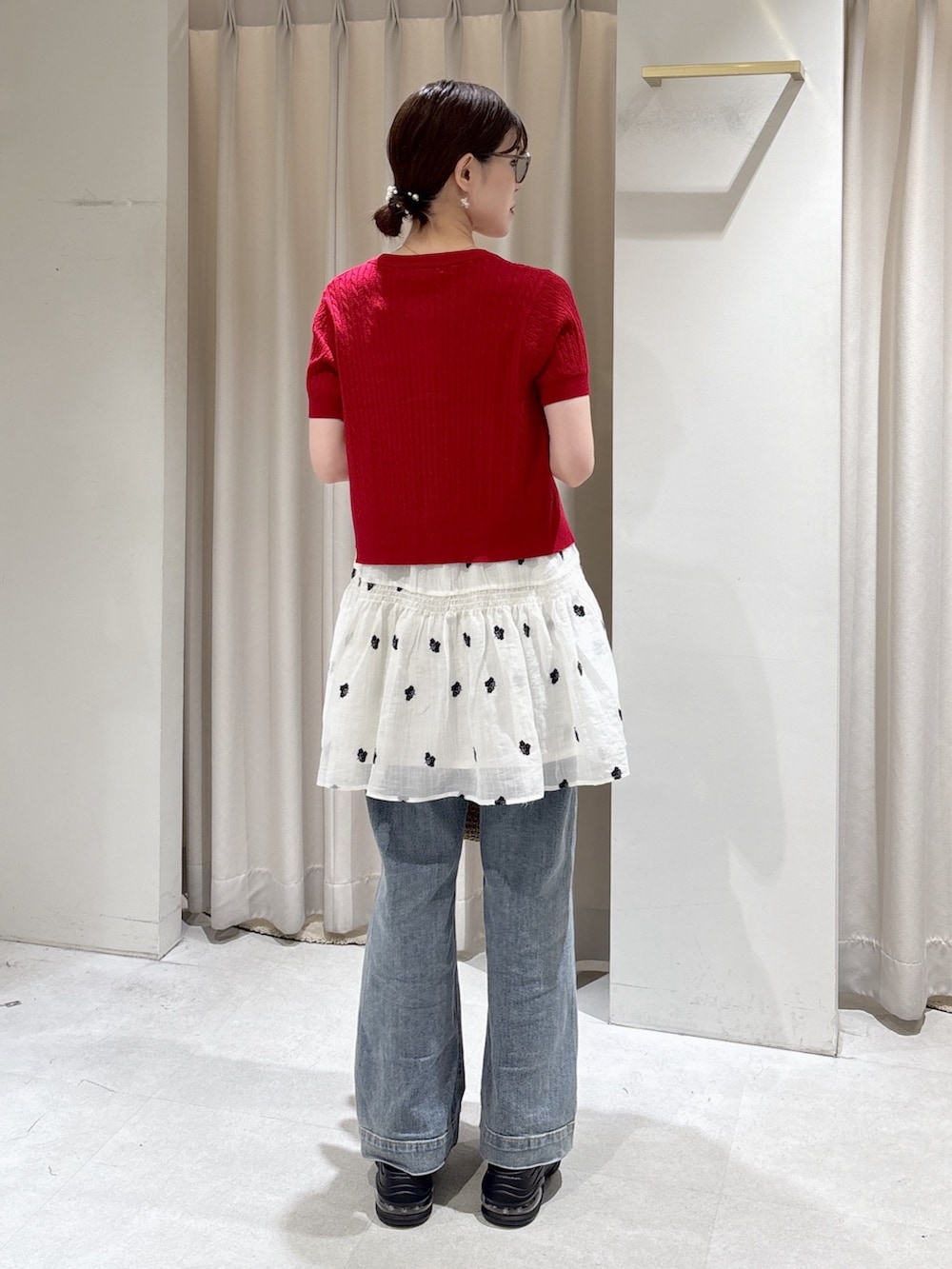 レッド系のニット/セーター、ブラック系のキャミソール、ブルー系のデニムパンツを着用したレディースの春コーディネートの4枚目の写真